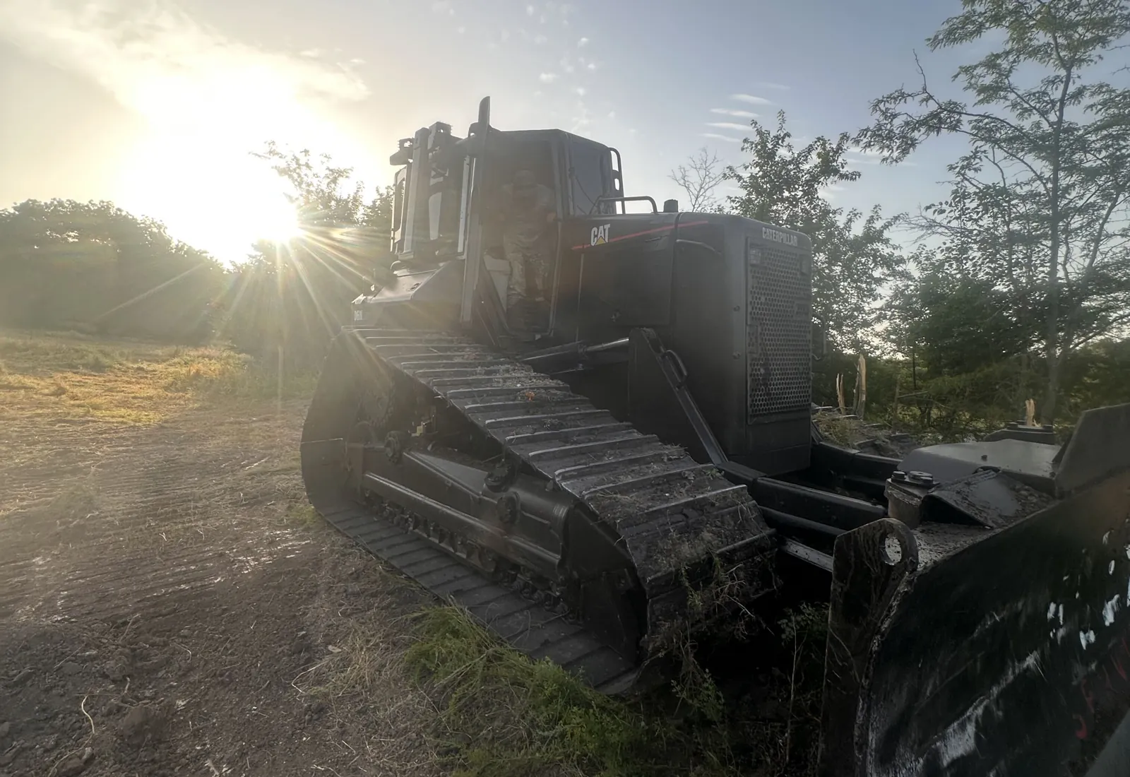 Dozer blade and tracks against the morning sun