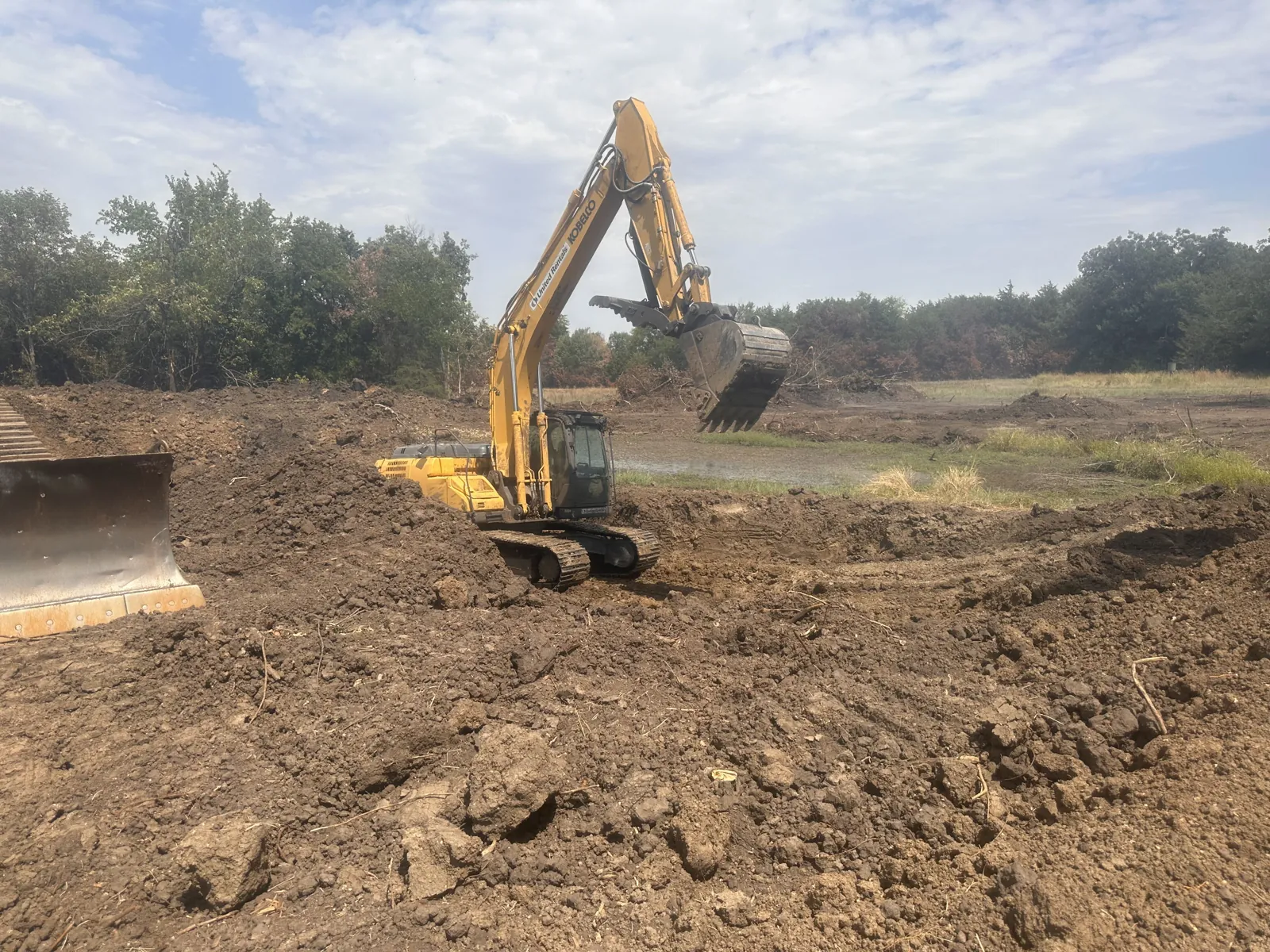 Excavator digging a pit with the spoil piled beside it