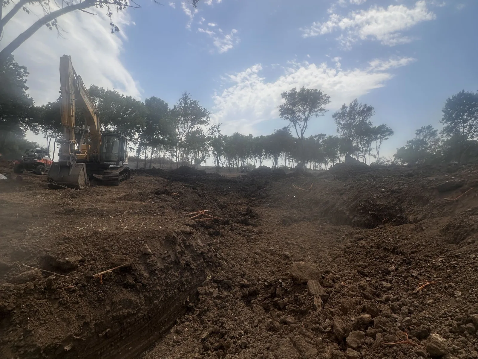 Excavator on the spoil pile at the edge of the new pond