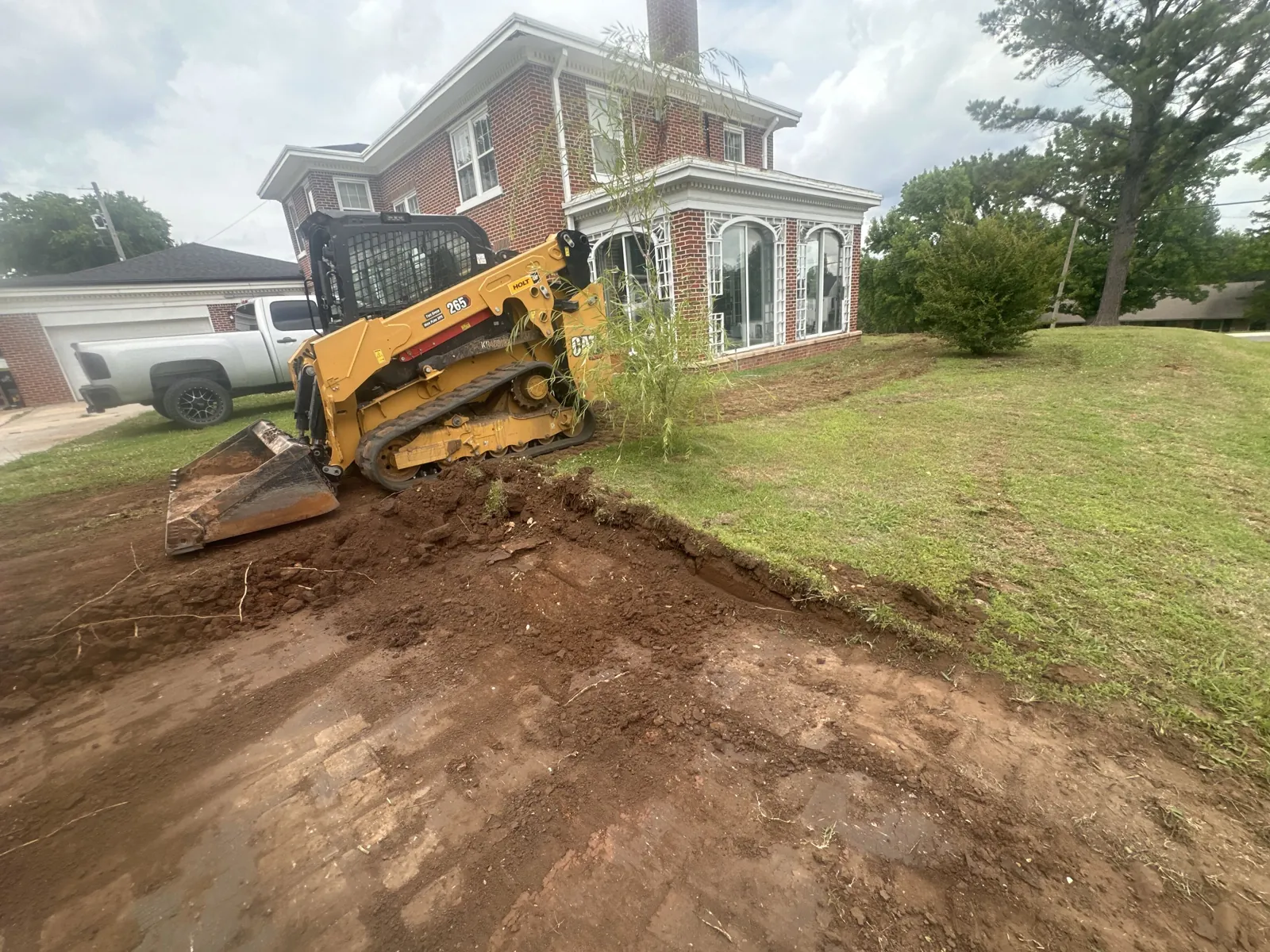 Tracked skid steer grading dirt in a front yard